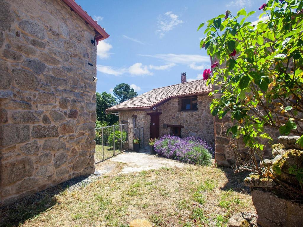 zewnętrzny widok na kamienny dom z kwiatami w obiekcie Traditional Apartment in Ribeira Sacra with Garden w mieście Castillón
