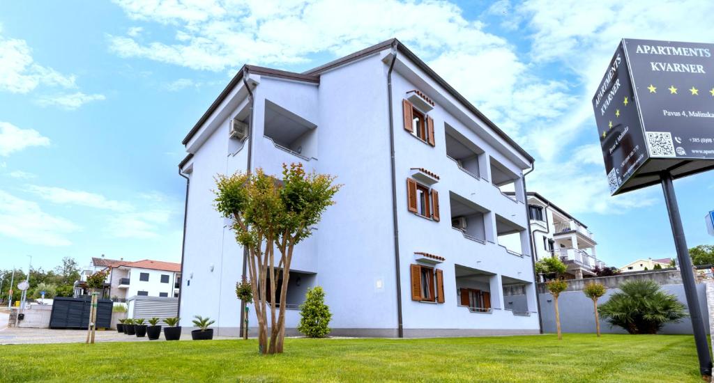 een wit gebouw met een bord ervoor bij Apartments Kvarner 2 in Malinska