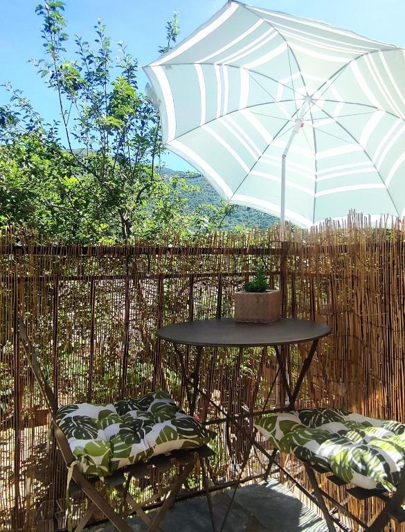 une table et deux chaises avec un parasol dans l'établissement Maison typique de village Corse , 10 min aéroport et de la mer, à Prunelli-di-Casacconi