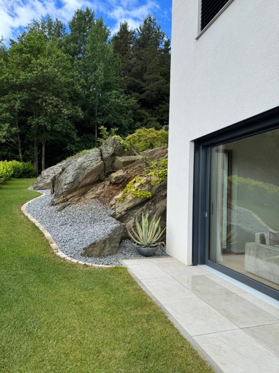 a building with a large glass door next to a garden at Anton's Apartment - Natur & See in Velden am Wörthersee