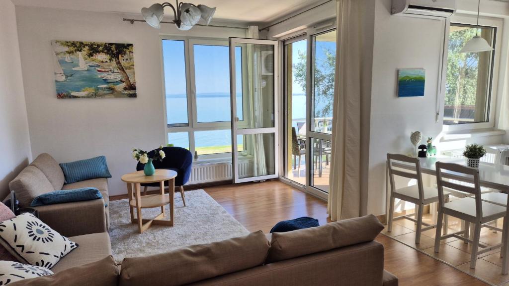 un soggiorno con un divano, un tavolo e delle sedie di Aloha Beach Terrace - Holiday Home a Siófok