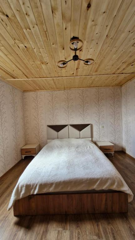 a bedroom with a large bed with a wooden ceiling at Guest house Calgmli in Kichkhuldashi