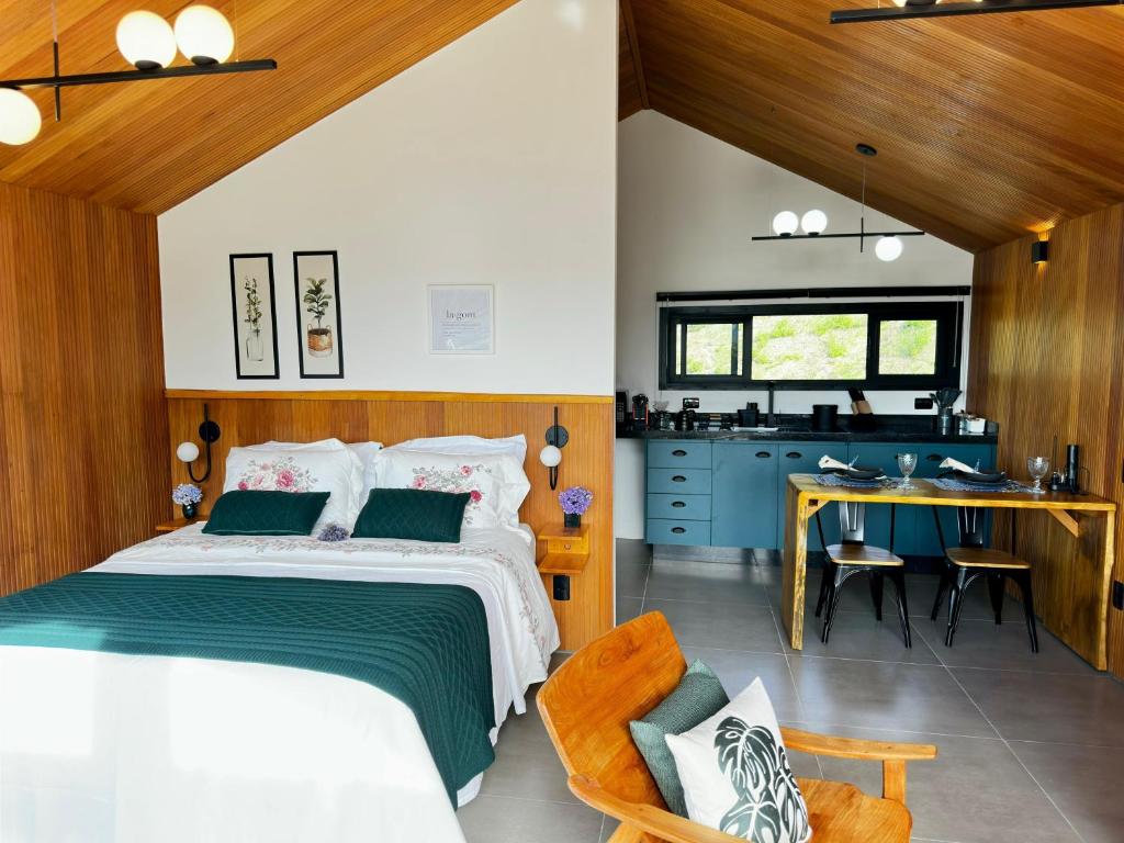 a bedroom with a large bed and a kitchen at Cabana Nórdica com Maravilhosa Vista da Serra in Gonçalves
