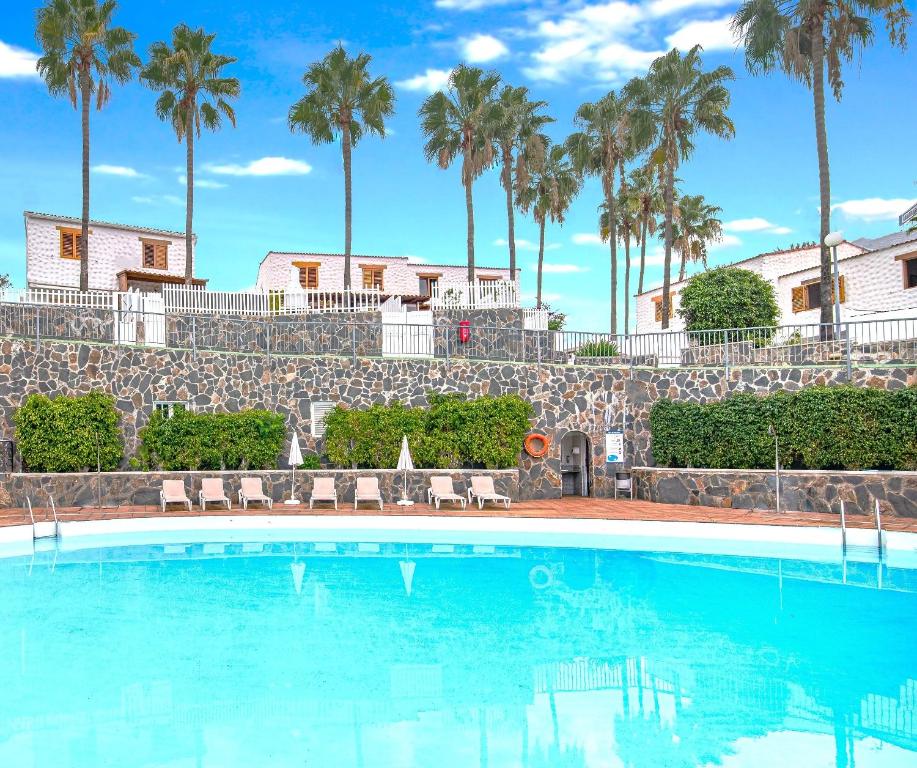 a swimming pool with palm trees in the background at Paradise Dúplex Garden & Beach Maspalomas in San Bartolomé