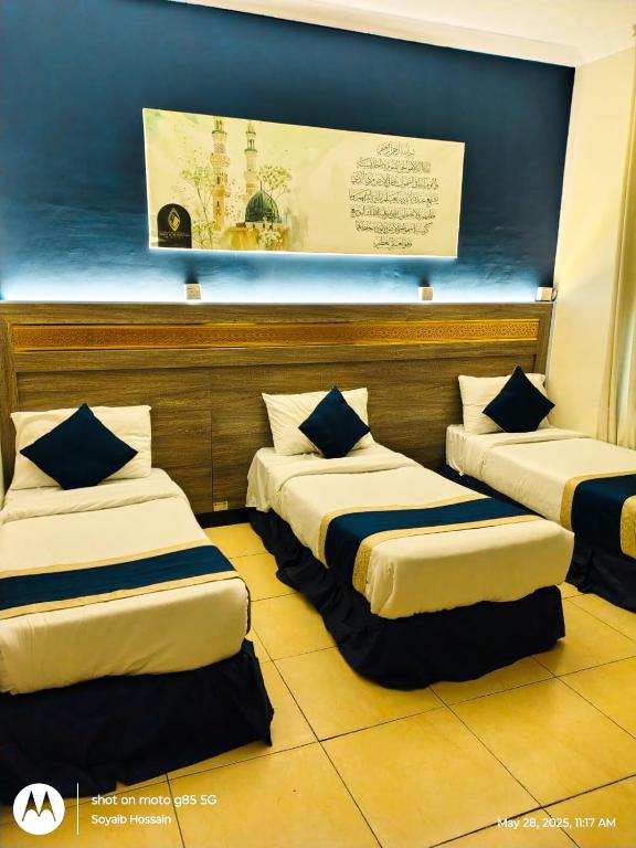 a room with three beds in it with a wall at Hotel Chatha Manoura- in Medina