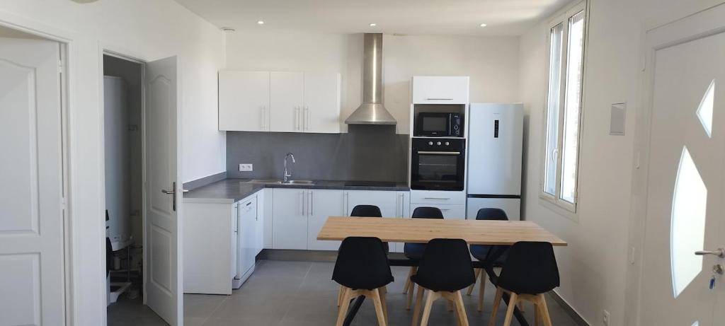 une cuisine avec une table en bois et quelques chaises noires dans l'établissement Appartement 4 p neuf dans haut de villa , clim, parking, jardin, à Saint-Laurent-du-Var