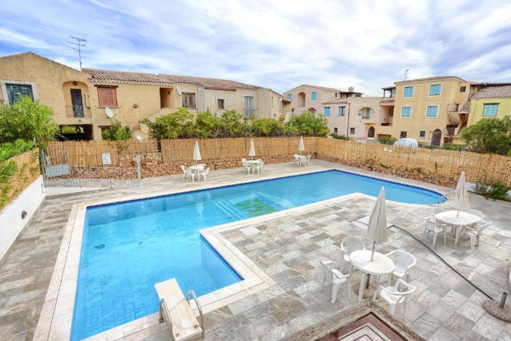 a swimming pool with tables and chairs next to a building at Sea&Sage 4 Spiagge Raggiungibili a piedi, Per famiglie con tutti i servizi in Porto San Paolo