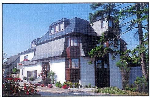 ein großes weißes Haus mit schwarzem Dach in der Unterkunft Hotel Morgensonne in Augustusburg