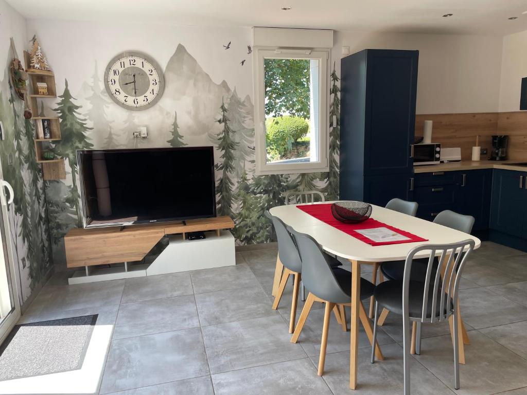 un salon avec une table et une télévision dans l'établissement Gîte des Brimbelles, à La Neuveville-devant-Lépanges