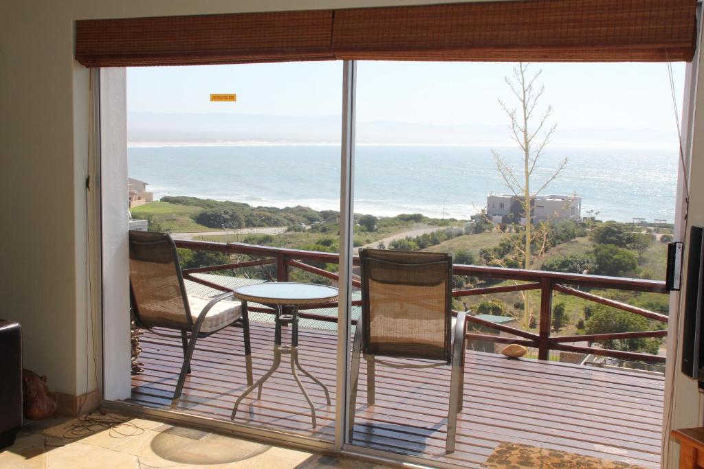 a balcony with two chairs and a table and the ocean at Surf View in Jeffreys Bay