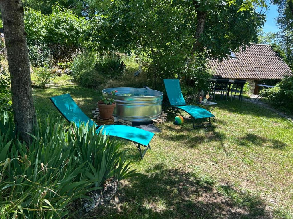 deux chaises bleues et un tonneau dans une cour dans l'établissement Le Dolmen, charme sport et détente, à Saint-Chels