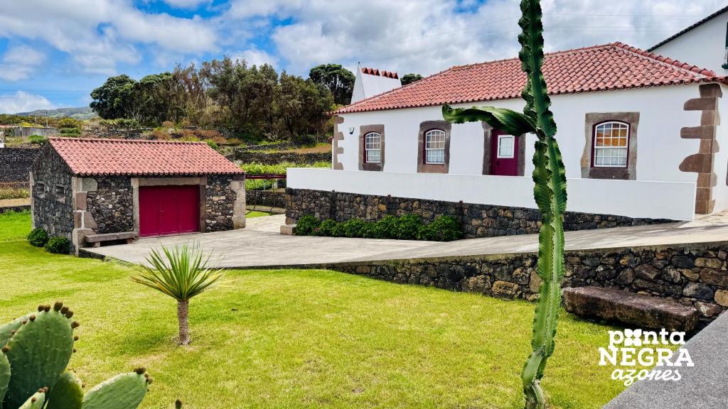 una casa con una porta rossa e un cortile verde di Casa da Hortênsia Roxa by Ponta Negra Azores a Praia da Vitória