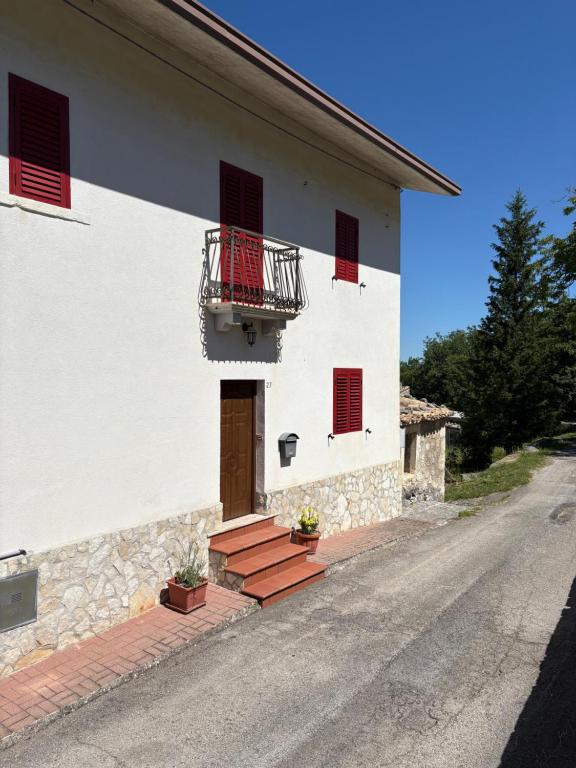 a white building with red windows and a balcony at Casa Lu' in San Tommaso
