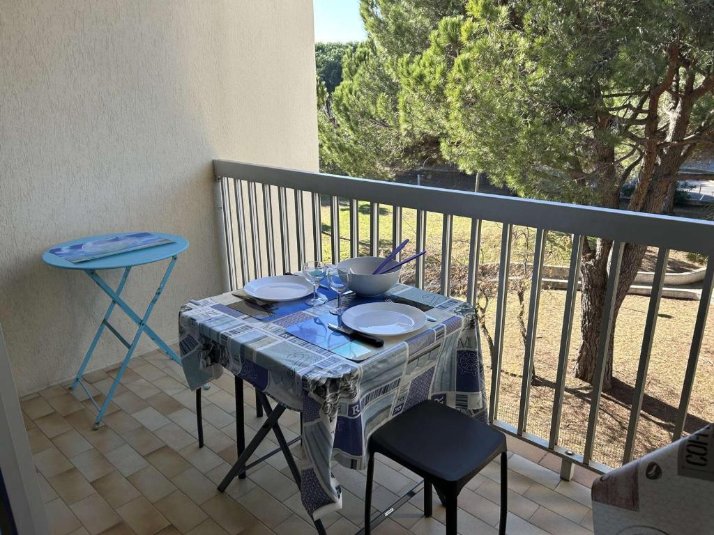 une table avec des assiettes et des bols sur un balcon dans l'établissement Studio Cabine Proche Plage avec Terrasse - Le Grau-du-Roi - FR-1-250-297, au Grau-du-Roi