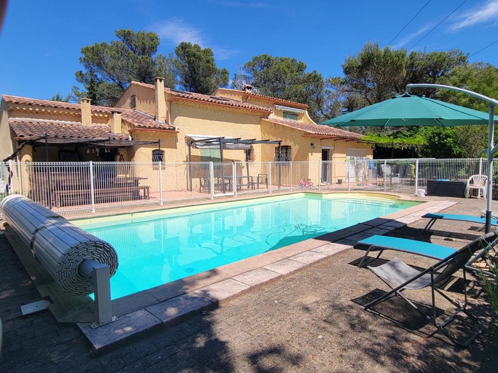 - une piscine avec un parasol et des chaises dans l'établissement Studio calme proche Aix & mer, à Gardanne