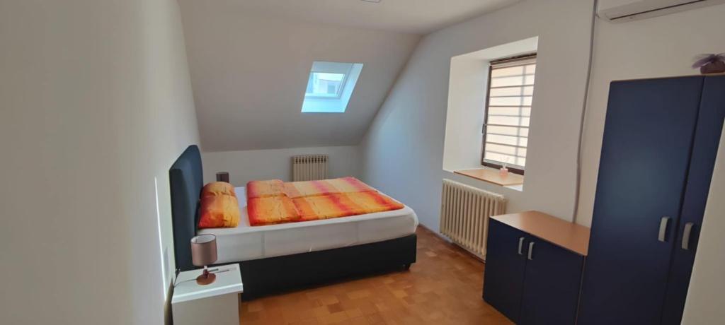 a bedroom with a bed with orange sheets and a window at No work in Ivišovo Greblje