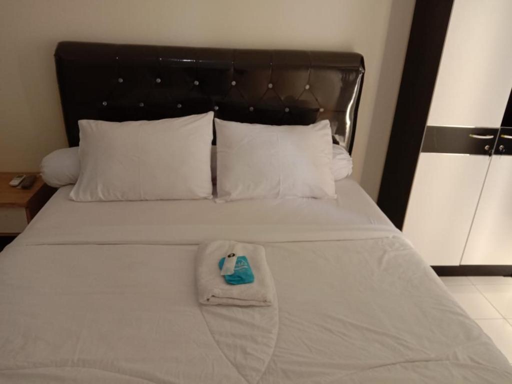 ein weißes Bett mit einem blauen Gegenstand darauf in der Unterkunft Dahoma lantai 6 in Tjikuda Tiga
