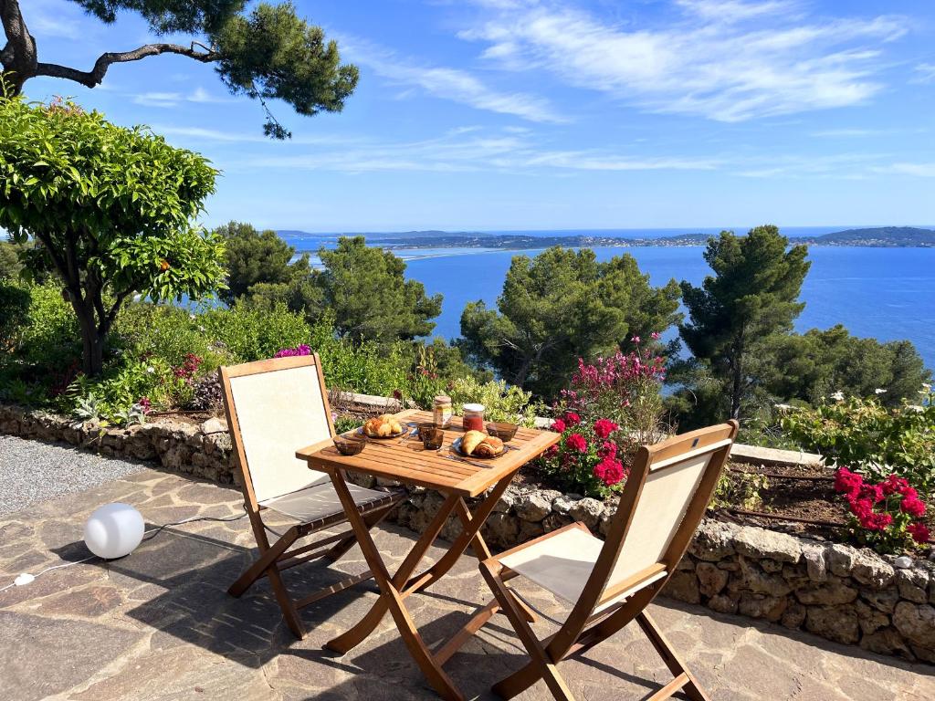 une table et des chaises avec vue sur l'eau dans l'établissement Expérience unique face à la mer et Porquerolles, à Carqueiranne