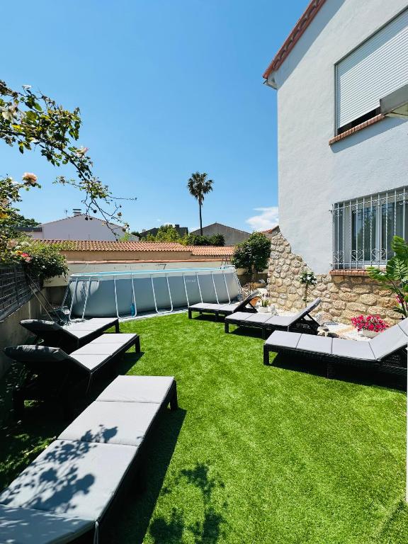 une pelouse avec des bancs et un bâtiment et un bâtiment dans l'établissement Maison,Piscine a 3km de la plage, à Villelongue-de-la-Salanque