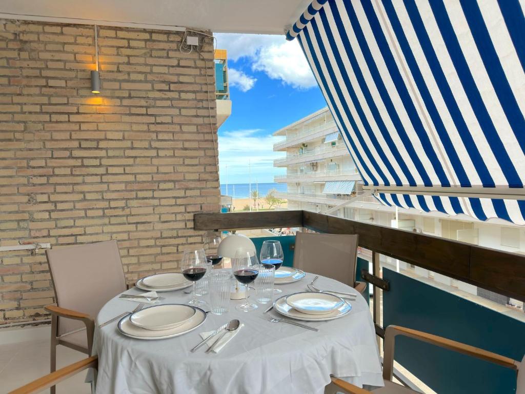 einen Tisch mit Tellern und Weingläsern auf dem Balkon in der Unterkunft Apartamento 3 habitaciones y 3 baños Playa de Gandía in Playa de Gandia