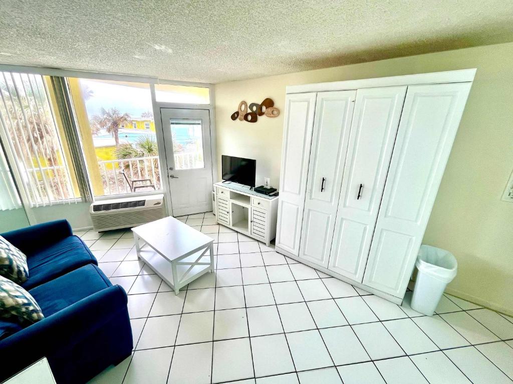 a living room with a blue couch and a tv at Coastal Cozy - Ocean View at Symphony Beach Club in Ormond Beach