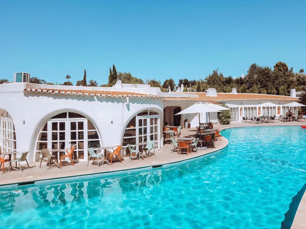 ein Resort mit einem Pool mit Tischen und Stühlen in der Unterkunft APT QUINTA PARAÍSO - Swimming Pool & Garden in Carvoeiro