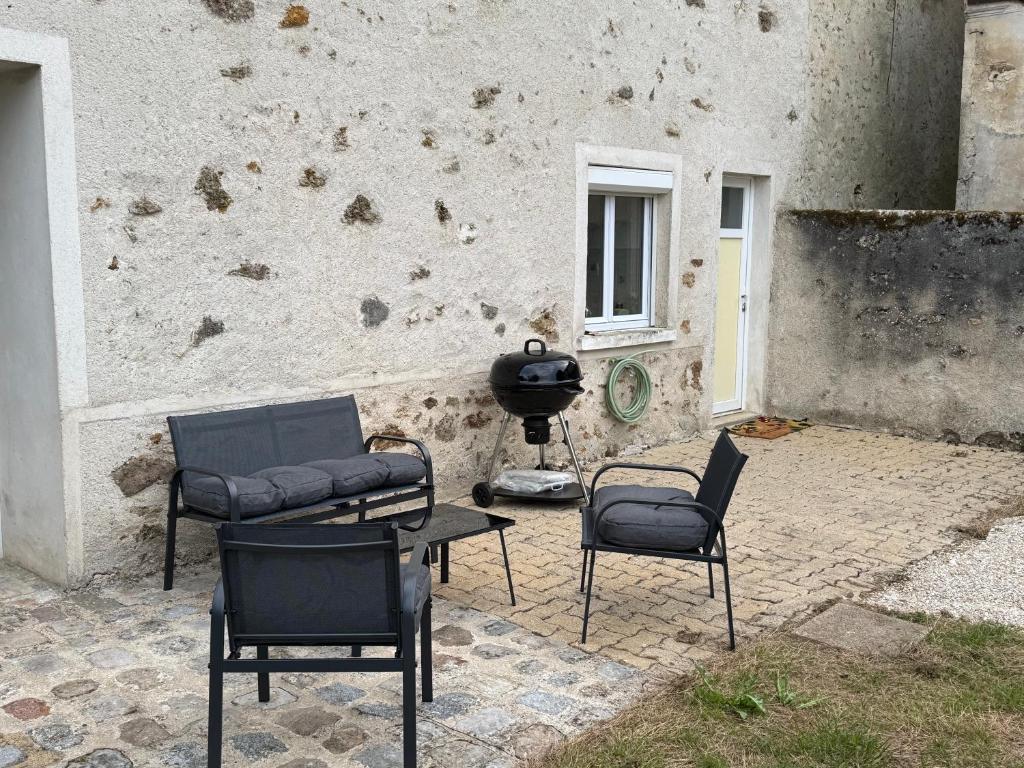 a patio with chairs and a grill in front of a building at Maison campagne proche Disney au calme in Saint-Cyr-sur-Morin
