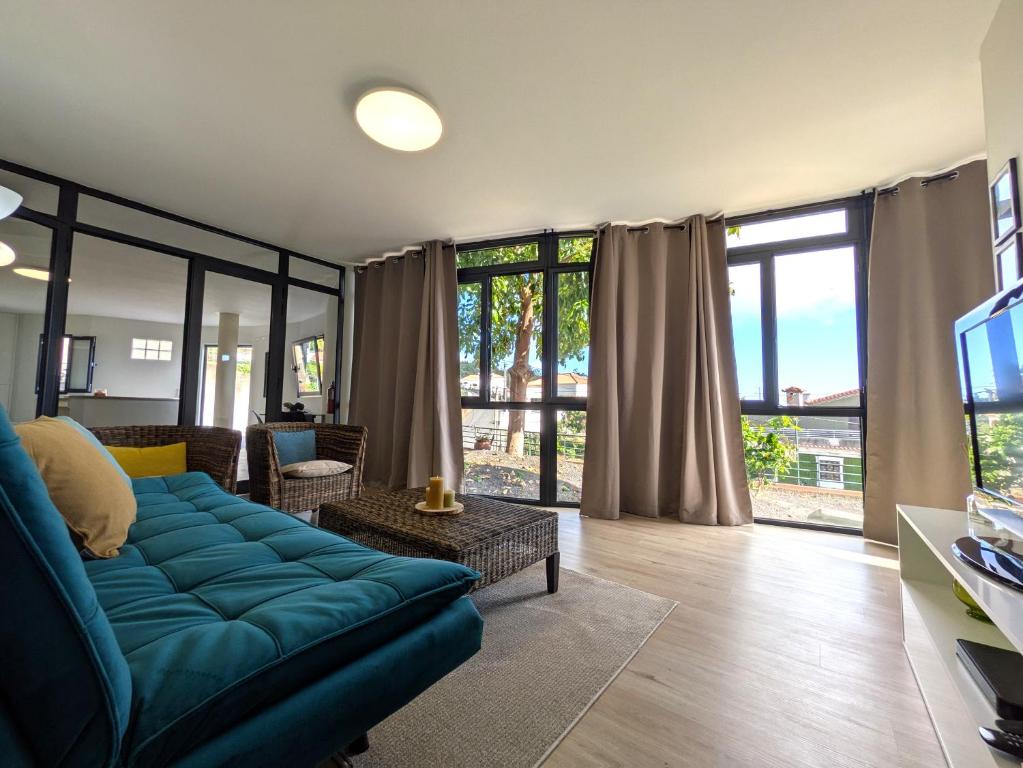 Una sala de estar con un sofá azul y un televisor. en Monte Gordo Accommodation, en Ribeira Brava