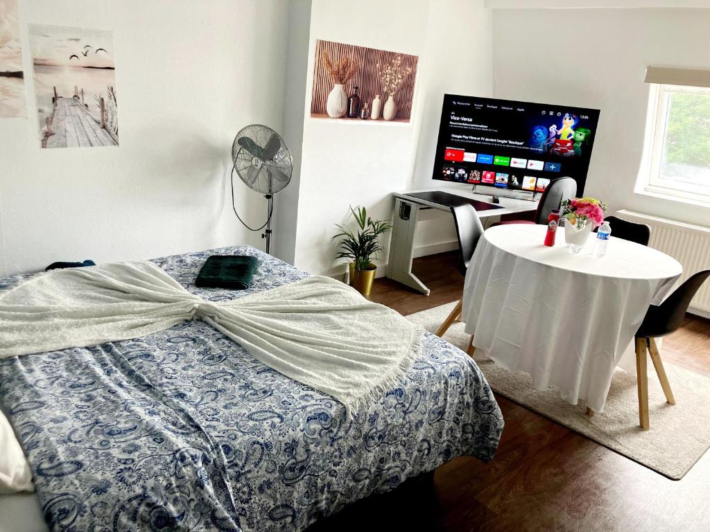 a bedroom with a bed with a table and a television at Gaby's House in Liège