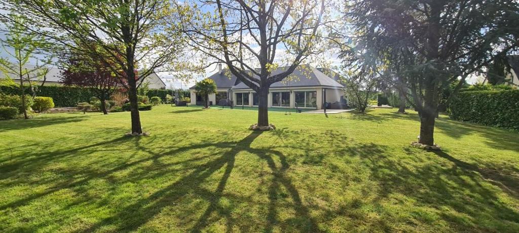une maison dans une cour avec des arbres dans l'herbe dans l'établissement Villa Neves, à Saint-Cyr-sur-Loire