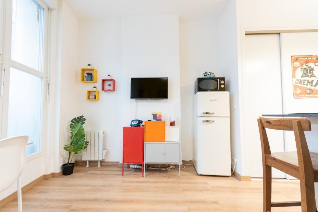 Habitación con nevera y TV en la pared. en Retro Pop, en Angers