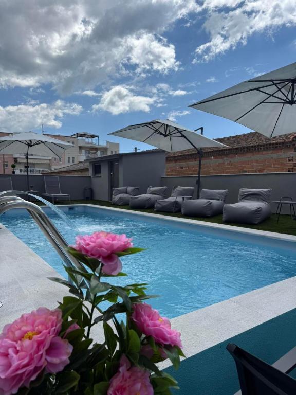 una vista di una piscina con fiori rosa e ombrelloni di STREET 90 Luxury Apartment a Keramotí