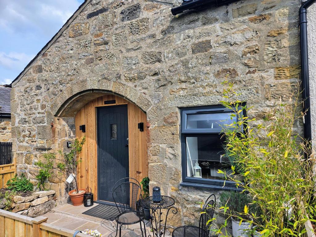 a stone house with a black door and a window at Cosy Coach House in Bellingham