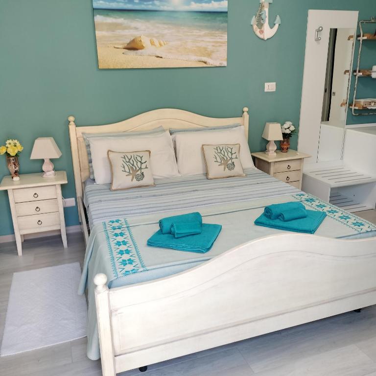 a bedroom with a white bed with two blue pillows on it at Affittacamere LiKele in Castelsardo