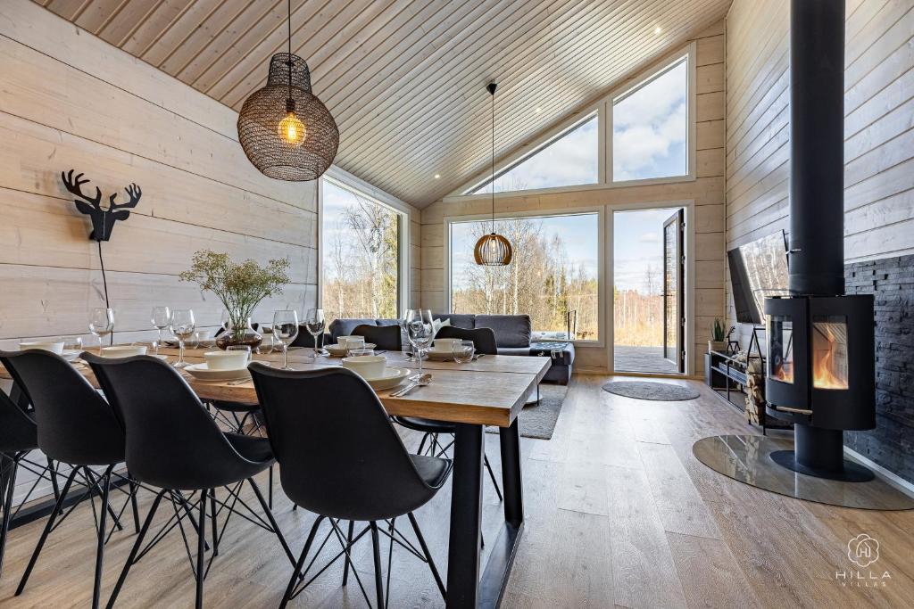a dining room with a table and a fireplace at Villa Cloudberry by Hilla Villas in Kittilä