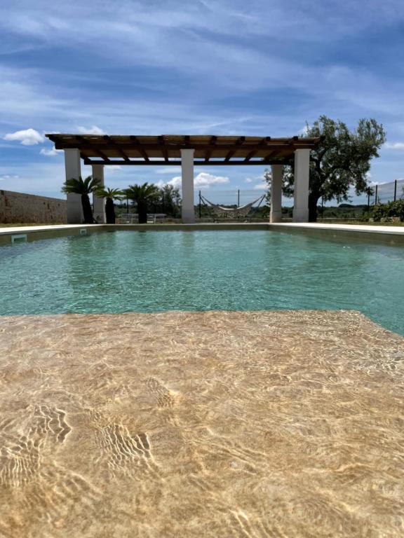 a swimming pool with a wooden pergola and water at Dimora San Michele in Castellana Grotte