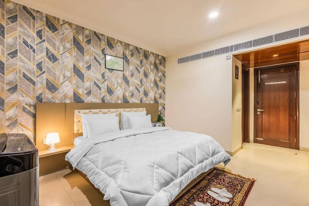 a bedroom with a large white bed and a wall at Eco-friendly vibes cozy space in Gurgaon