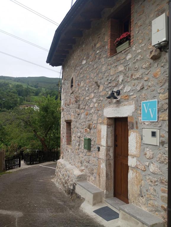 un edificio de piedra con una puerta y un cartel en él en La Cuestina, en Onís