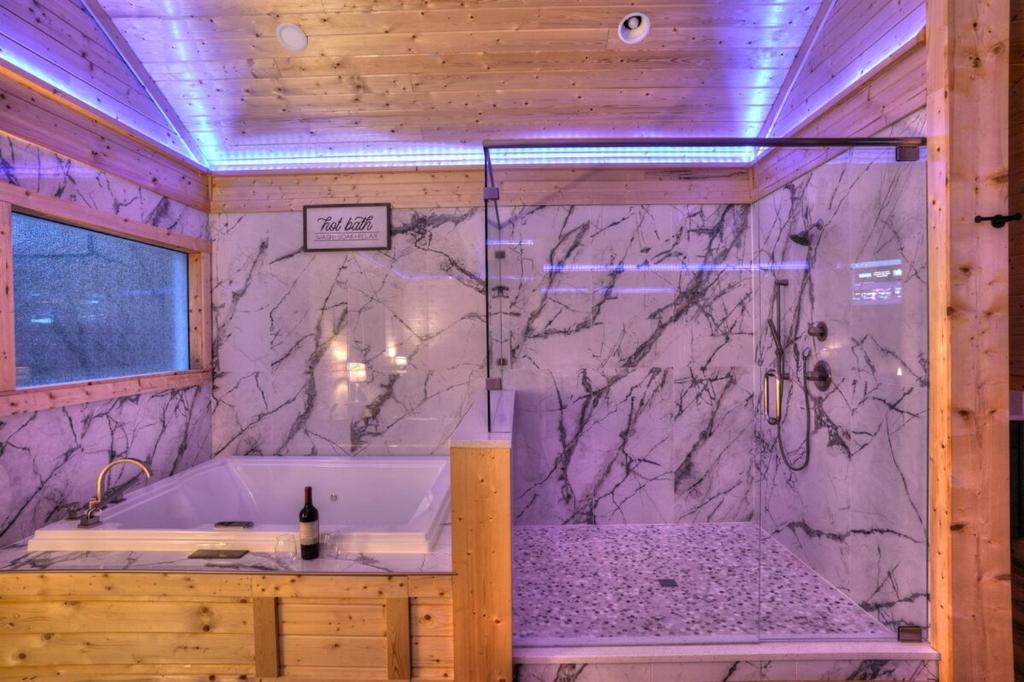 a bathroom with a tub and a marble wall at Brand New Luxury Cabin Full of Amenities 