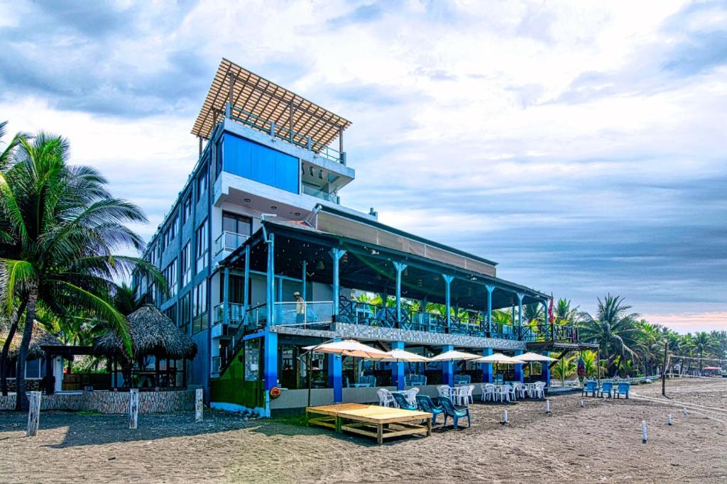 a building on the beach with chairs and umbrellas at Hotel Playa Paraíso in Monterrico