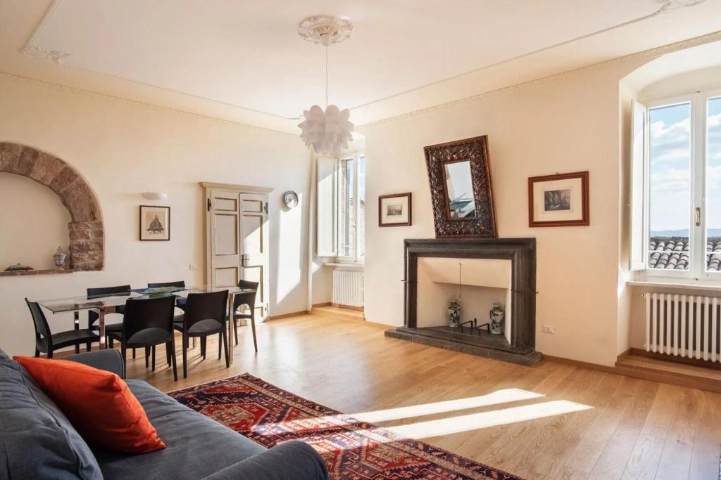 a living room with a table and a fireplace at Casa Clara - Fino a 10 Posti letto in centro ad Assisi - ItalyWeGo in Assisi