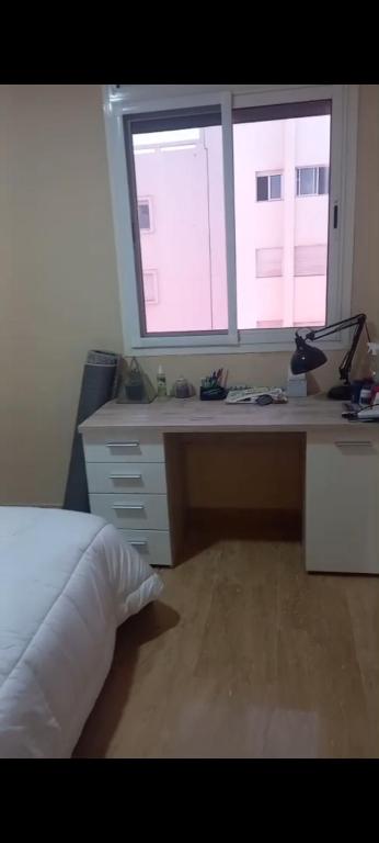 a bedroom with a bed and a desk with two windows at Apartamento en Rabat al lado del Mar in Oulad Akkou