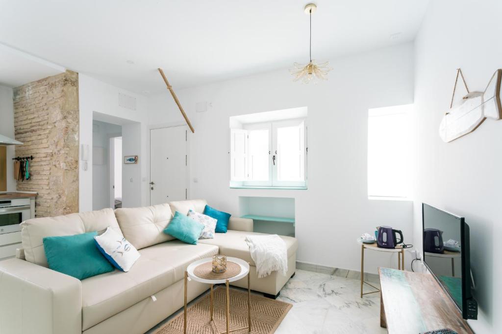een witte woonkamer met een witte bank en blauwe kussens bij Fantástico ático en el casco antiguo en a la playa in Cádiz