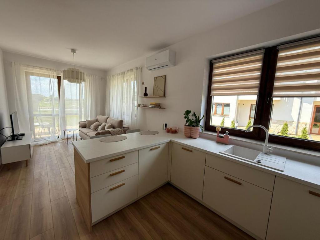 a kitchen with white cabinets and a living room at Apartamenty Pastelove Nałęczów in Nałęczów