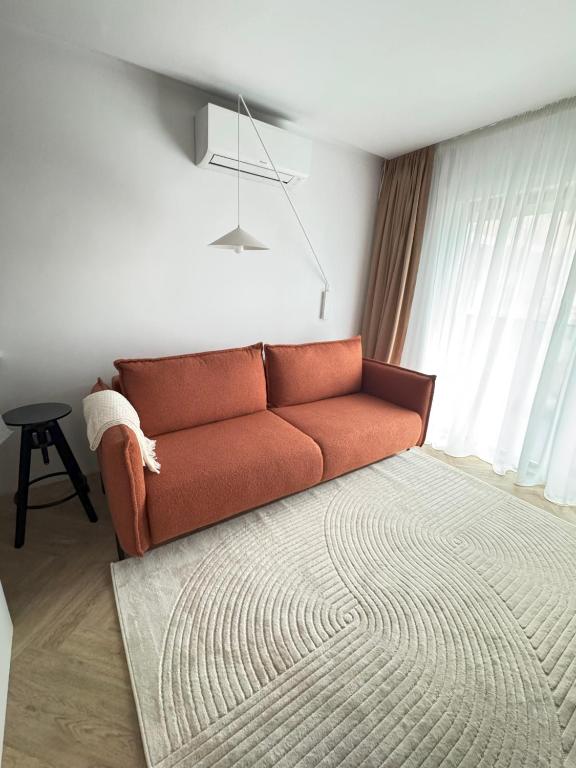 an orange couch in a living room with a rug at Cozy Studio Sulina in Sulina