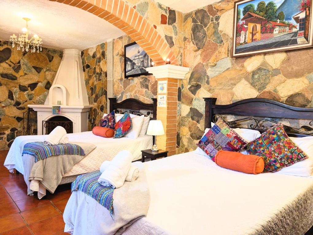 two beds in a room with a stone wall at Casa Quetzalli, La Recolección in Antigua Guatemala