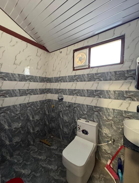 bagno con servizi igienici e orologio a parete di Hostello Manali a Manāli