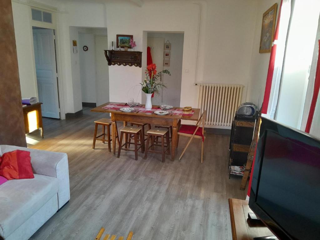 un salon avec une table, des chaises et une télévision dans l'établissement le montagne, à Briançon
