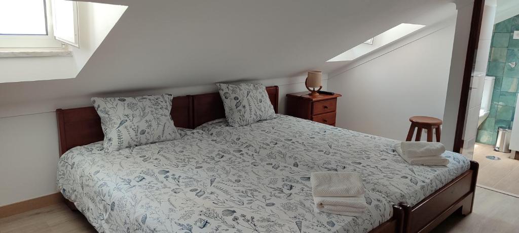 een slaapkamer met een groot bed met witte lakens en kussens bij Casinha da Marina - totalmente renovada in Nazaré