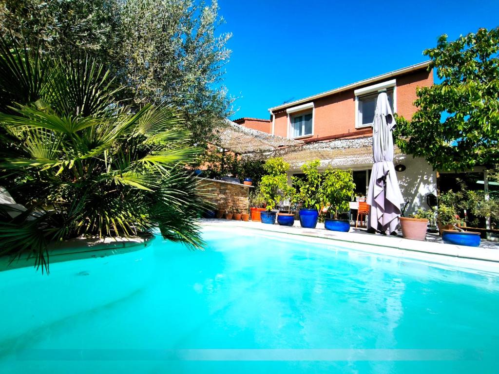 - une grande piscine avec un parasol dans l'établissement Cocon Provençal, à Gardanne